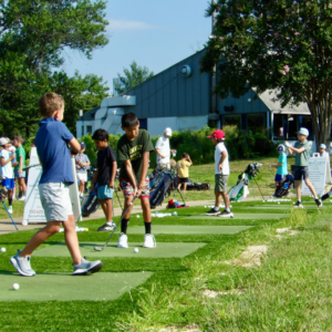 Junior golf camp at Reston National Golf Course driving range, with juniors practicing full swings.