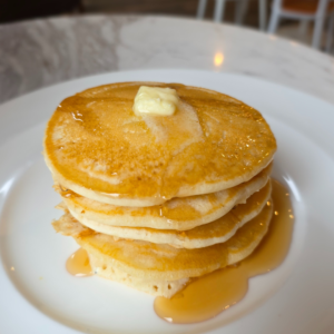 Stack of fluffy pancakes served at Reston National Golf Course topped with syrup and butter, showcasing breakfast offerings for guests.