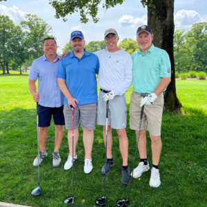 Foursome of golfers posing on the first tee at Reston National Golf Course, preparing to tee off in a golf tournament,