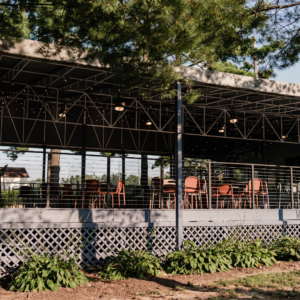 Covered patio at Reston National Golf Course clubhouse, featuring outdoor seating with shade for dining, events, and post-round gatherings.