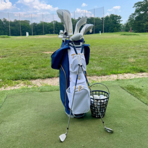 Rental golf club set on the driving range at Reston National Golf Course with a basket of range balls.