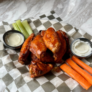 Basket of crispy chicken wings served with ranch dressing, carrot sticks, and celery at Reston National Golf Course.